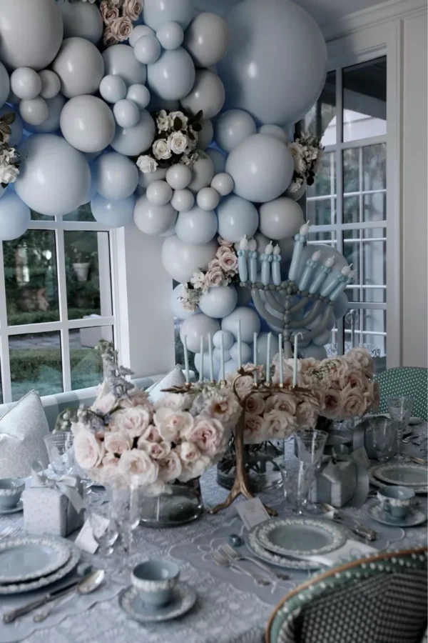 blue and white hanukkah table with blue balloons and roses