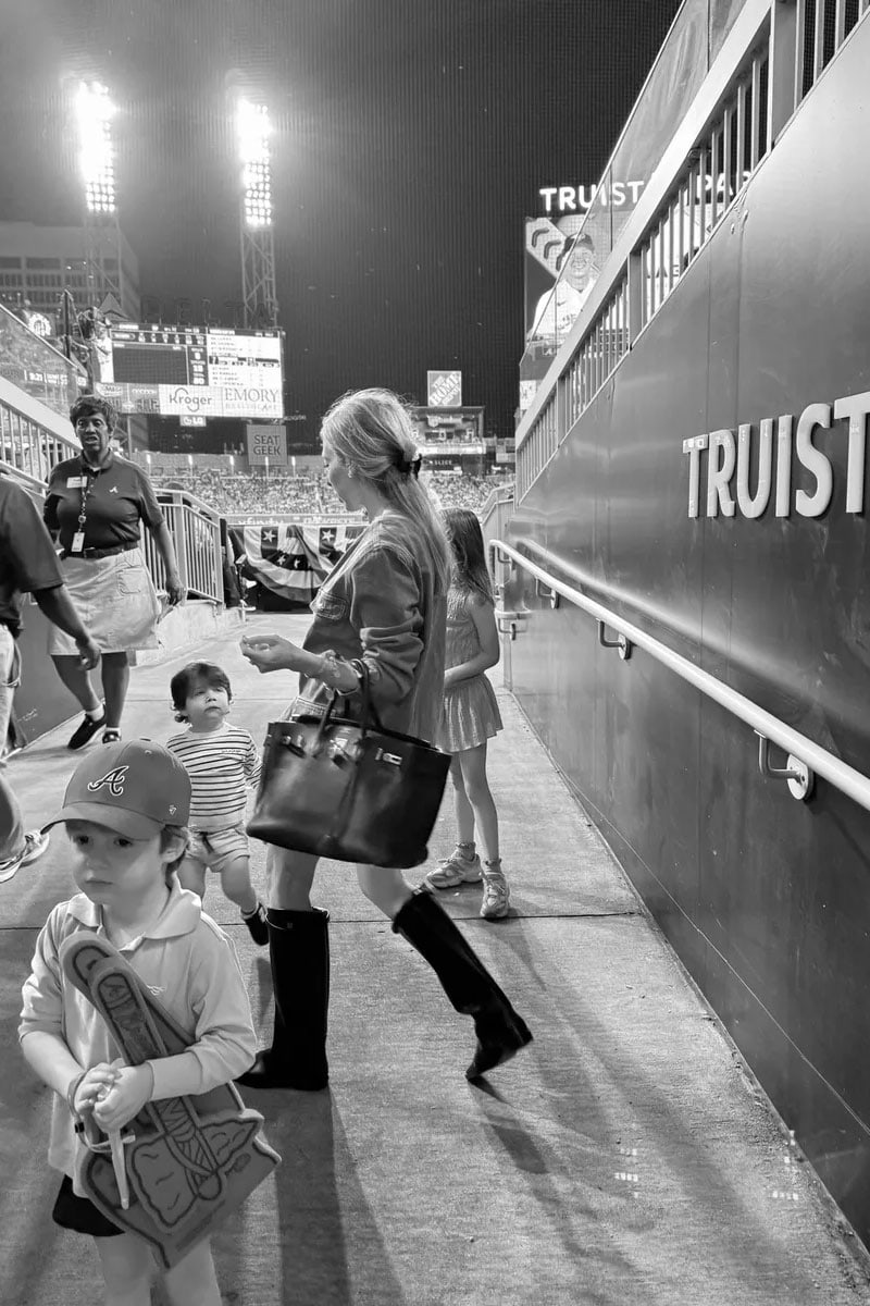 Emily at the Braves game wearing Anine Bing jacket and knee high boots