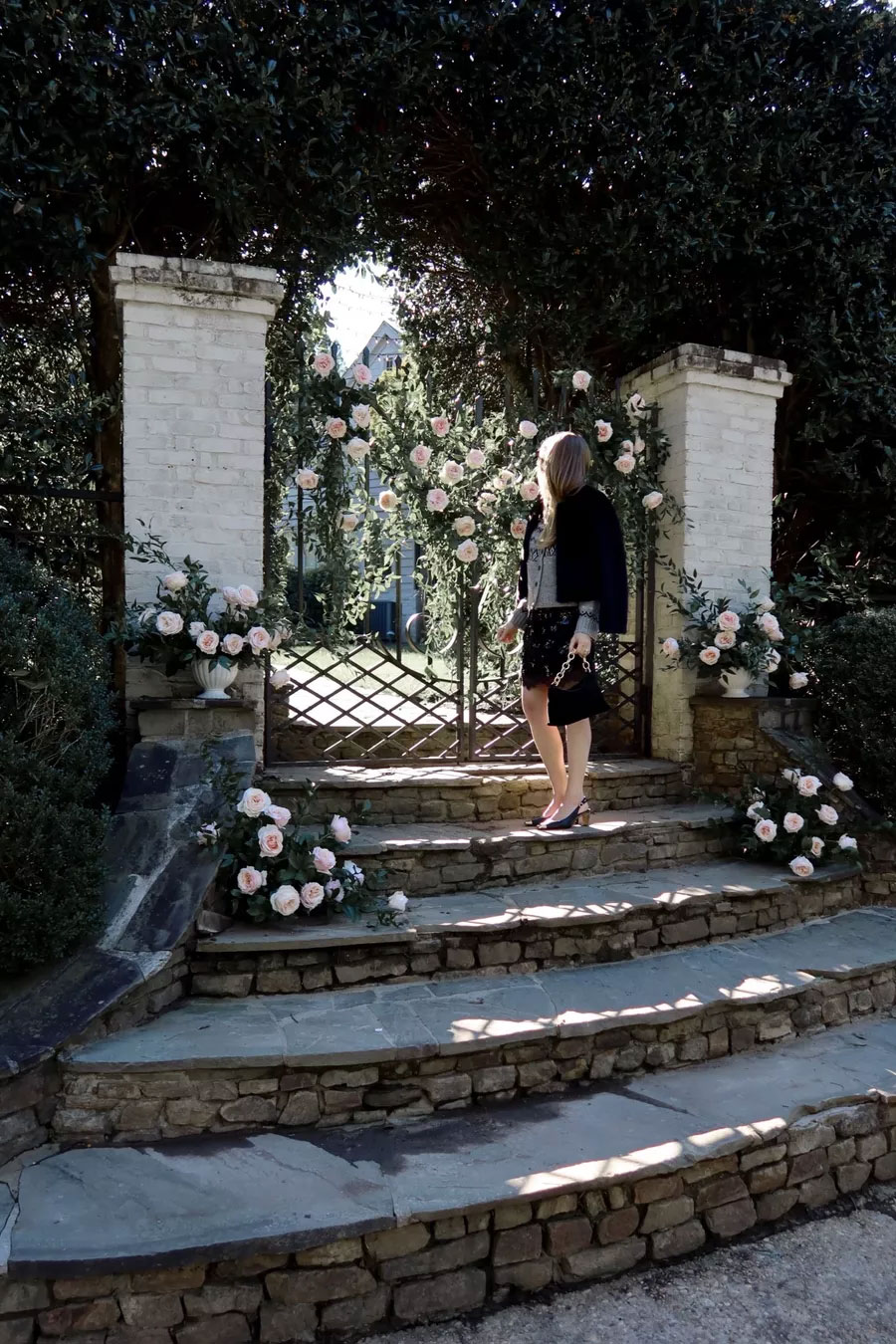 Emily wearing J crew fall 2025 in front of gate with garden roses