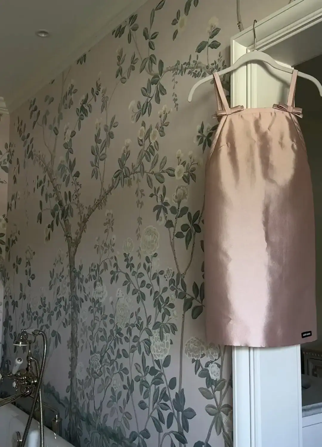 Miu Miu pink bow Silk and wool mini-dress hanging in front of floral wallpaper