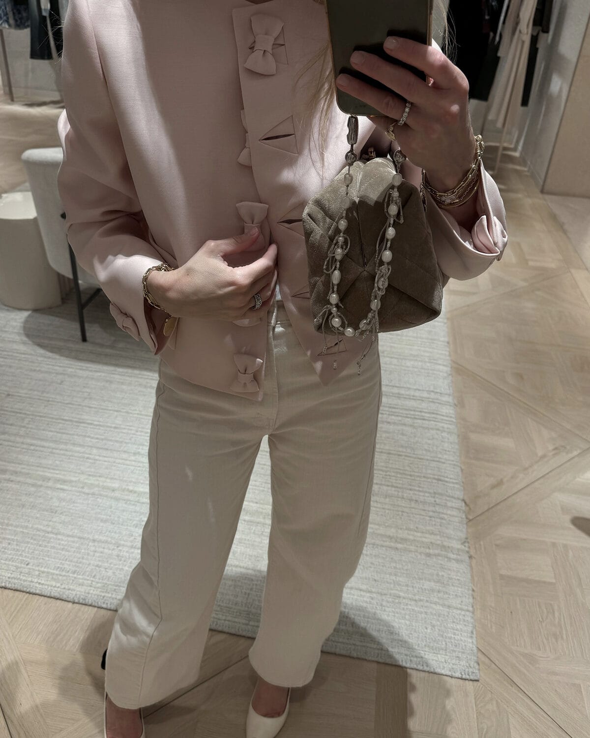 Emily wearing pink button jacket with bows and cream jeans
