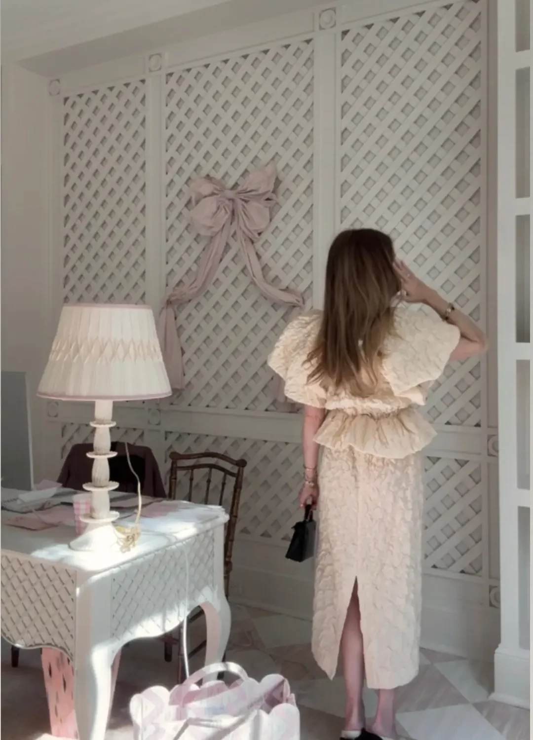 Emily wearing Ulla Johnson puff sleeve lace peplum skirt and top set in office with pink bow and decor