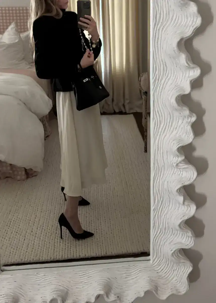 Emily wearing black jacket, white pleated jenni kayne skirt, and Gianvito black pumps